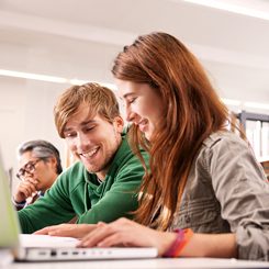 Zwei junge Sprachschüler sitzen am Laptop. 